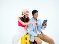 Happy Asian couple, young woman with beach hat and man in denim shirt sit on suitcase. Royalty Free Stock Photo