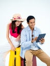 Happy Asian couple, young woman with beach hat and man in denim shirt sit on suitcase. Royalty Free Stock Photo