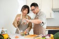 Happy Asian couples, husband and wife, are cooking a healthy salad bowl in the kitchen together Royalty Free Stock Photo