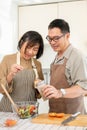 Happy Asian couples, husband and wife, are cooking a healthy salad bowl in the kitchen together Royalty Free Stock Photo