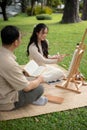 A happy Asian daughter and father are enjoying picnicking in a green park on the weekend together Royalty Free Stock Photo