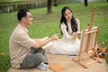 A happy Asian daughter and father are enjoying picnicking in a green park on the weekend together Royalty Free Stock Photo