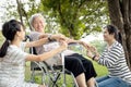 Happy asian daughter,granddaughter holding hand her senior mother care,support and massaging hands of elderly people at park,old