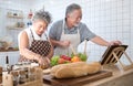 Happy asian elder senior couple cooking fresh meal in kitchen at home