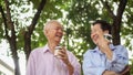 Happy Asian elderly couple morning walk in green city while drin Royalty Free Stock Photo