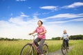 Happy Asian elderly seniors couple biking in farm