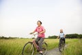 Happy Asian elderly seniors couple biking in the park with blue Royalty Free Stock Photo