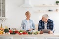 Happy asian family couple cooking food, vegetable salad in kitchen together at home with device Royalty Free Stock Photo