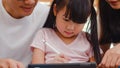 Happy Asian family dad, mom and daughter using computer tablet technology sitting sofa in living room at house. Self-isolation, Royalty Free Stock Photo