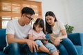 Happy Asian family dad, mom and daughter using computer tablet technology sitting sofa in living room at house. Self-isolation, Royalty Free Stock Photo