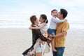 Happy asian family dad and mom with their children boy and girl, parents carrying their children and kissing with love on sandy Royalty Free Stock Photo