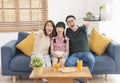 Happy Asian family eating popcorn and watching tv together on sofa at home living room. leisure and people concept Royalty Free Stock Photo