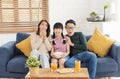 Happy Asian family eating popcorn and watching tv together on sofa at home living room. leisure and people concept Royalty Free Stock Photo