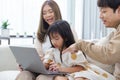 Happy asian family father mother and child daughter having fun using laptop computer sitting on couch in living room at home. Royalty Free Stock Photo