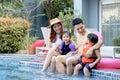 Happy Asian family, father mother daughter and son enjoy outdoor activity at swimming pool, kid and parent sitting by blue water Royalty Free Stock Photo