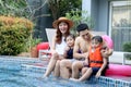 Happy Asian family, father mother daughter and son enjoy outdoor activity at swimming pool, kid and parent sitting by blue water Royalty Free Stock Photo