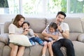 Happy Asian family, father, mother daughter and son singing karaoke on the sofa in the living room with happy smiling face Royalty Free Stock Photo