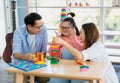 Happy Asian family father mother with a handicapped daughter with down syndrome play together. They are playing with a colorful