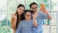 Happy Asian family father mother and handicapped daughter with down syndrome standing and smiling at a camera in a living room at