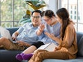 Happy Asian family father mother and handicapped down syndrome child sitting on a couch relaxedly in a living room at home. The