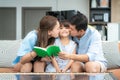 Happy Asian family with Father and Mother kiss in their daughter cheek together while sitting in living room at home. Love emotion
