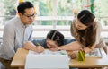 Happy Asian family father mother sitting a and looking at daughter with down syndrome wearing eyeglasses using a color pencil Royalty Free Stock Photo