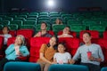 Asian family father, mother, son and grandmother watching movie at the cinema happily on weekends Royalty Free Stock Photo