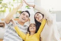 Happy asian family forming house roof with their hands at home