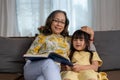 happy asian family grandmother reading to granddaughter book at home Royalty Free Stock Photo