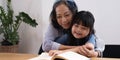 happy asian family grandmother reading to granddaughter child book at home Royalty Free Stock Photo