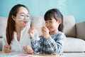 Happy Asian family that has a mother and daughter sitting playing enjoying and activity together at home and sunlight morning