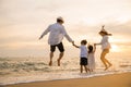 Happy Asian family have fun jumping together on beach in holiday at sunset time Royalty Free Stock Photo