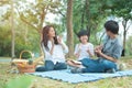 Happy asian family have leisure in public park.Father playing guitar with mother and son clap hands together with enjoying and Royalty Free Stock Photo