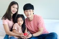 Happy Asian family having fun in bedroom. Father, mother and daughter girl hugging each other to show warm love, mom and dad, Royalty Free Stock Photo