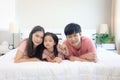 Happy Asian family having fun in bedroom. Father, mother and daughter playing together during lying on white bed. Parents having Royalty Free Stock Photo