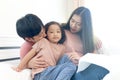 Happy Asian family having fun in bedroom. Father, mother and daughter playing together during lying on white bed. Parents having Royalty Free Stock Photo