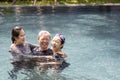 Happy asian family having fun and hug in swimming pool,smiling mother and child girl daughter playing with her senior grandmother Royalty Free Stock Photo