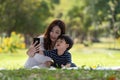 Asian family having fun mother and her son taking selfie with mobile phone in the park together, love and happiness people concept Royalty Free Stock Photo