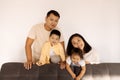 Happy Asian family at home. A Korean couple and their cute little kids on the sofa in the living room Royalty Free Stock Photo