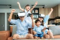 Happy Asian family at home on living room sofa having fun while they are looking mother and father playing games using virtual Royalty Free Stock Photo