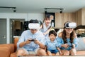 Happy Asian family at home on living room sofa having fun while they are looking mother and father playing games using virtual Royalty Free Stock Photo