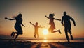 Happy asian family jumping together on the beach in holiday. Silhouette of the family holding hands enjoying the sunset on the Royalty Free Stock Photo