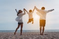 Happy asian family jumping together on the beach in holiday vacation. Silhouette of the family holding hands enjoying the sunset Royalty Free Stock Photo