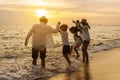 Happy asian family jumping together on the beach in holiday vacation. Silhouette of the family holding hands enjoying the sunset Royalty Free Stock Photo