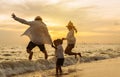 Happy asian family jumping together on the beach in holiday vacation. Silhouette of the family holding hands enjoying the sunset Royalty Free Stock Photo