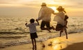 Happy asian family jumping together on the beach in holiday vacation. Silhouette of the family holding hands enjoying the sunset Royalty Free Stock Photo