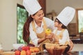 Happy Asian family in kitchen. Mother and son in chef hat preparing food in home kitchen together. People lifestyle and Family.
