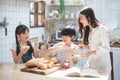 Happy asian family in the kitchen. mother and son and daughter spread strawberry yam on bread, leisure activities at home