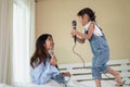 Happy Asian family loving children, kid and her sister holding microphone and singing together on bed in bedroom Royalty Free Stock Photo