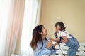 Happy Asian family loving children, kid and her sister holding microphone and singing together on bed in bedroom Royalty Free Stock Photo